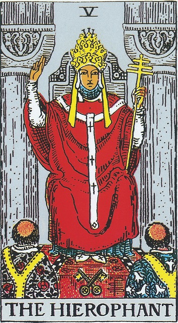 Tarot Card - The Hierophant 
A priest- or holy man- sits on a throne.  Next to him are two pillars, his right hand is raised in religious blessing, and his left holds a scepter with three crosses.  He wears red robes which have three crosses on the front and is wearing a three-tiered crown.  At his feet are students, learning the wisdom which only he can teach; one is clad in roses, the other, lilies.  Beneath his feet are crossed keys. 