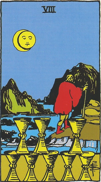 The Eight of Cups
A figure wearing a red cloak and boots, and carrying a staff, walks up a rocky path, away from the edge of a river.  On the opposite side of the river, in the foreground of the card are eight cups, positioned in such a manner that it seems that one is missing.  In the distance are rocky outcroppings rising out of a river or waterway.  It is night; there is a blue sky and a sun within a moon overlooking the scene